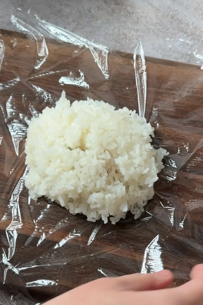 Salmon filling covered with rice and ready to be shaped into a Japanese rice ball