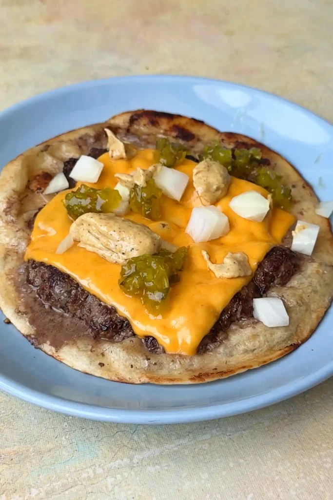 Smash burger taco topped with burger sauce, onions, and pickles