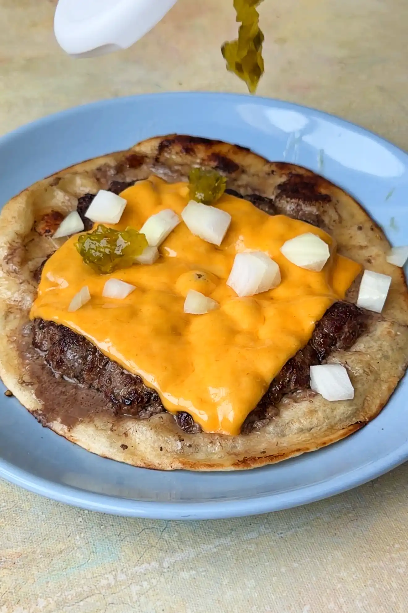 Adding pickles to a smash burger taco