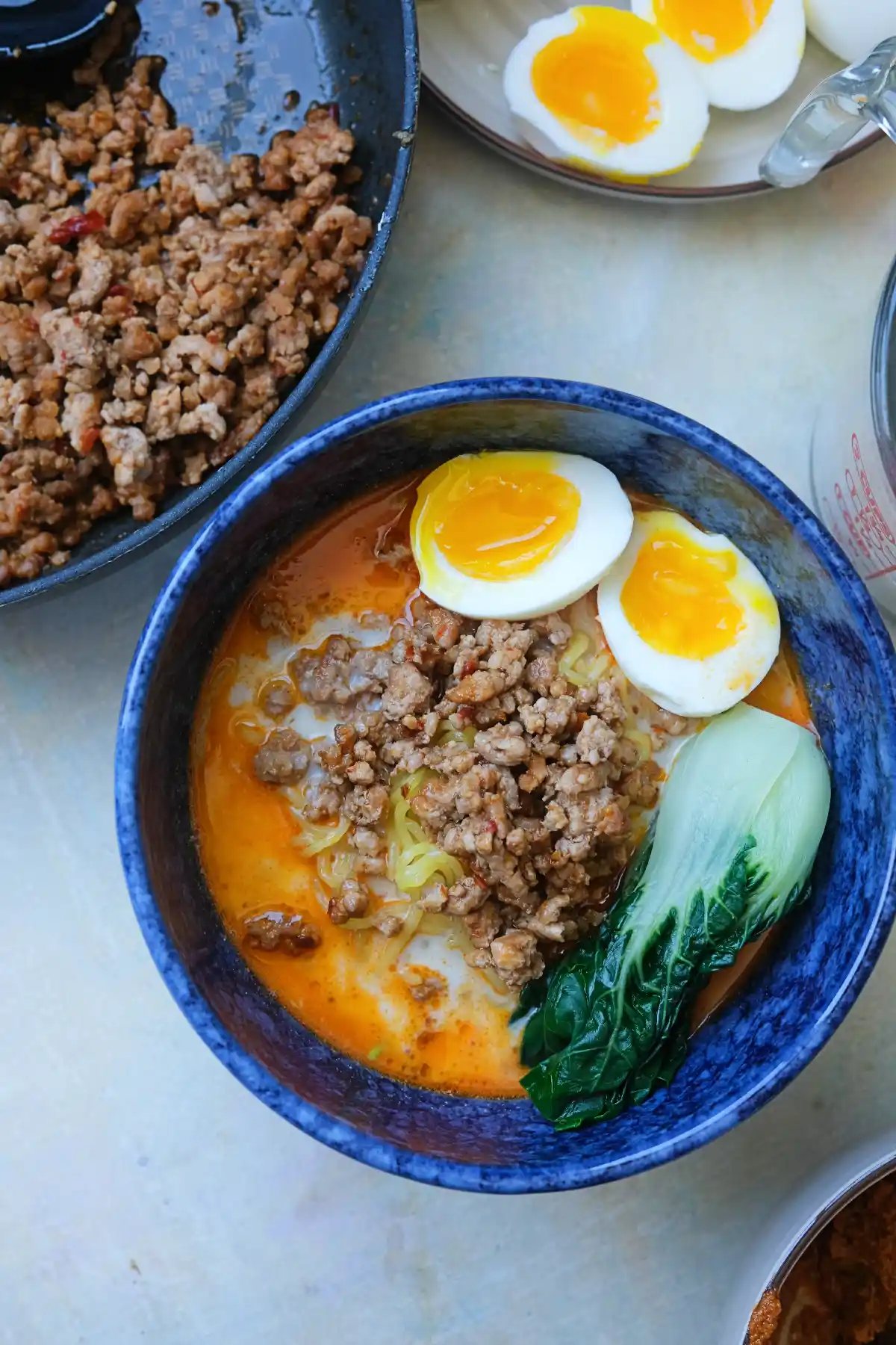 Overhead view of homemade tantanmen ramen with ground pork, jammy eggs, and bok choy in a rich sesame broth
