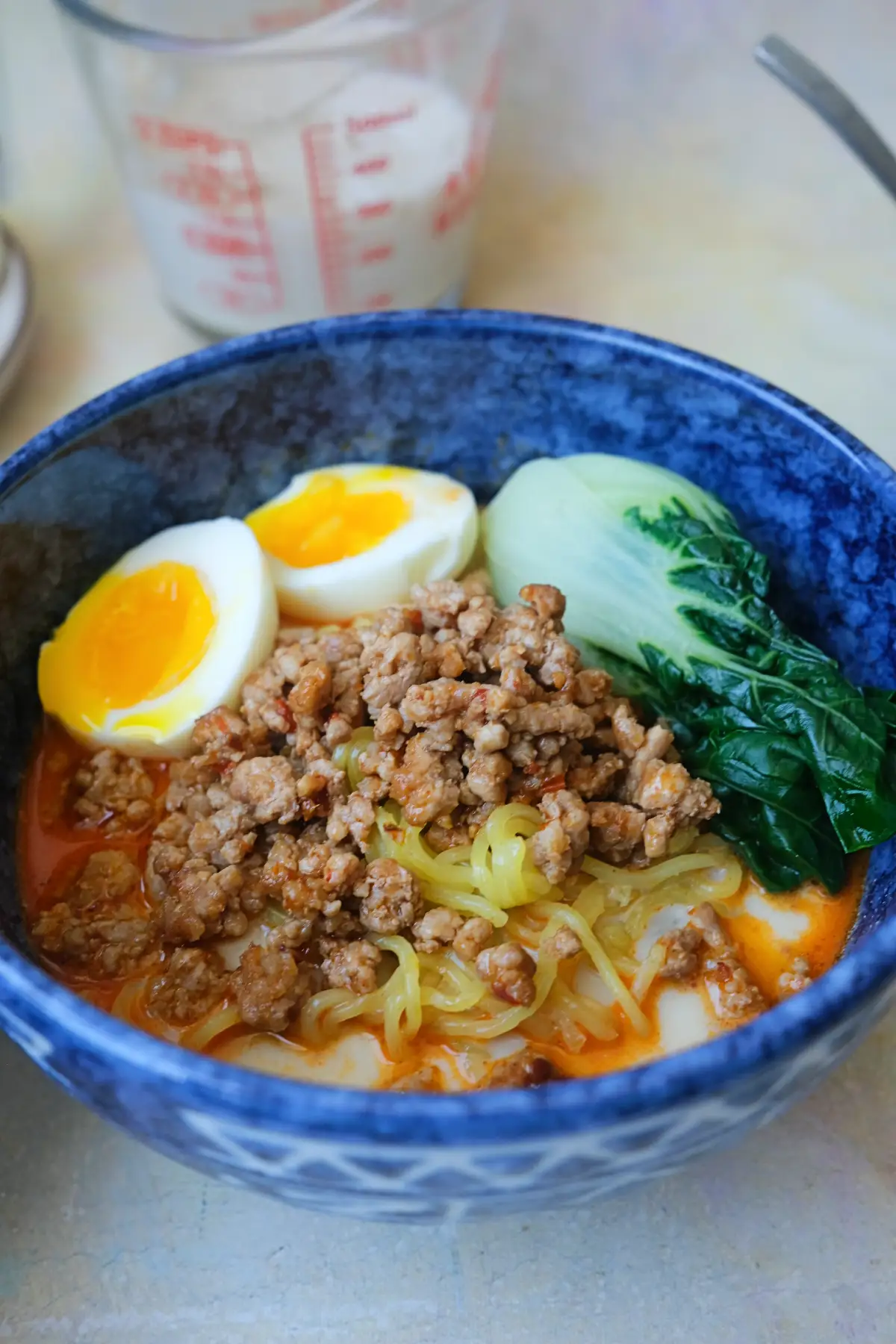 Close-up of tantanmen ramen with chewy noodles, savory pork, soft-boiled eggs, and creamy spicy broth