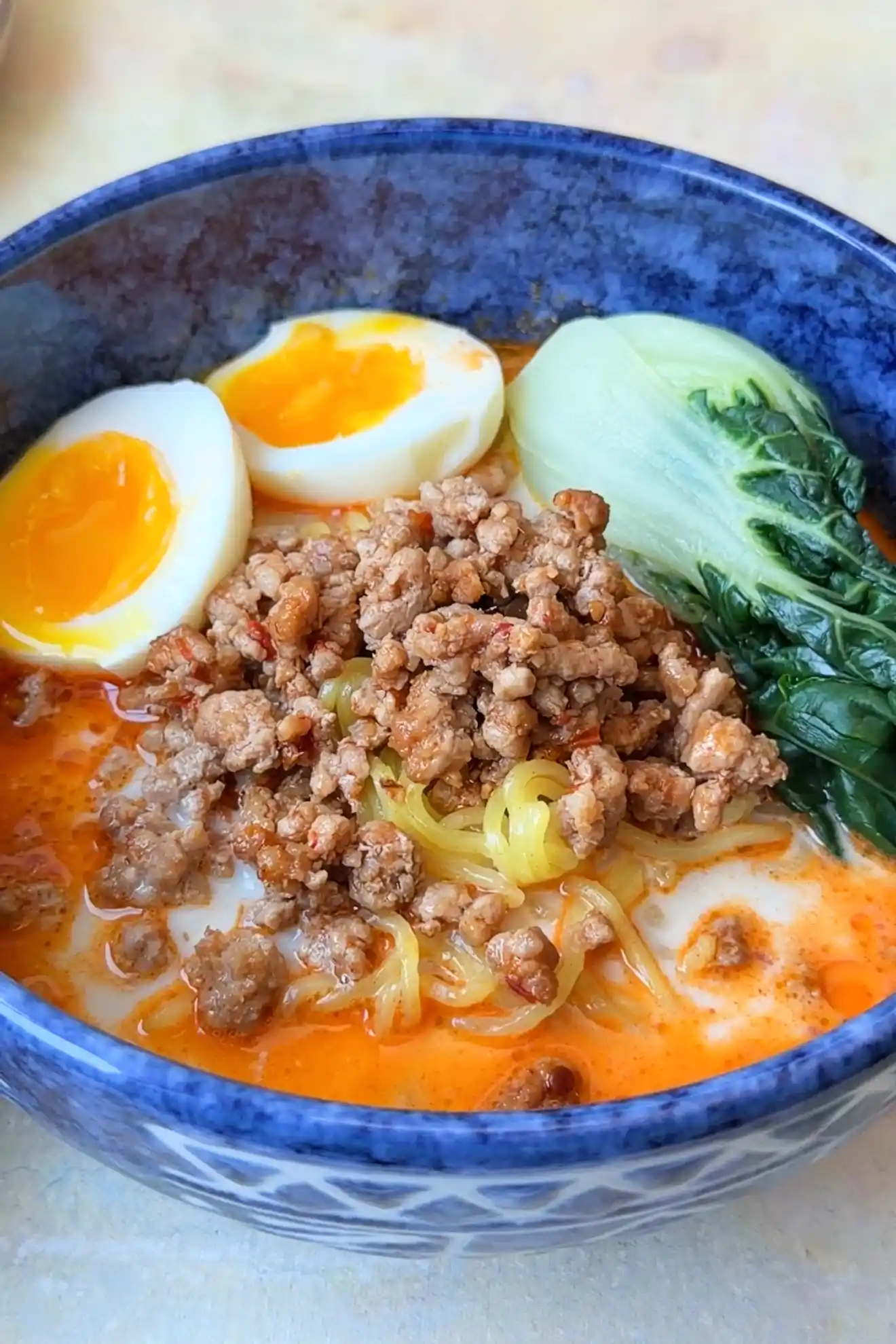 Detailed view of tantanmen ramen featuring ground pork, ramen noodles, bok choy, and soft-boiled eggs