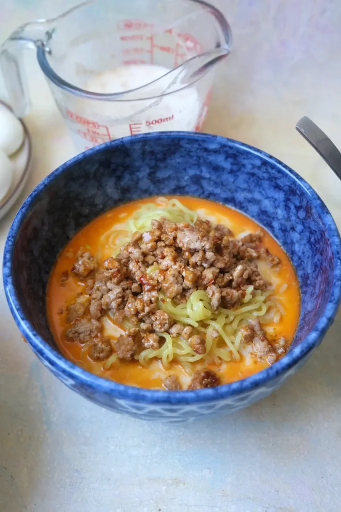 Seasoned ground pork spooned over ramen noodles in a bowl of tantanmen