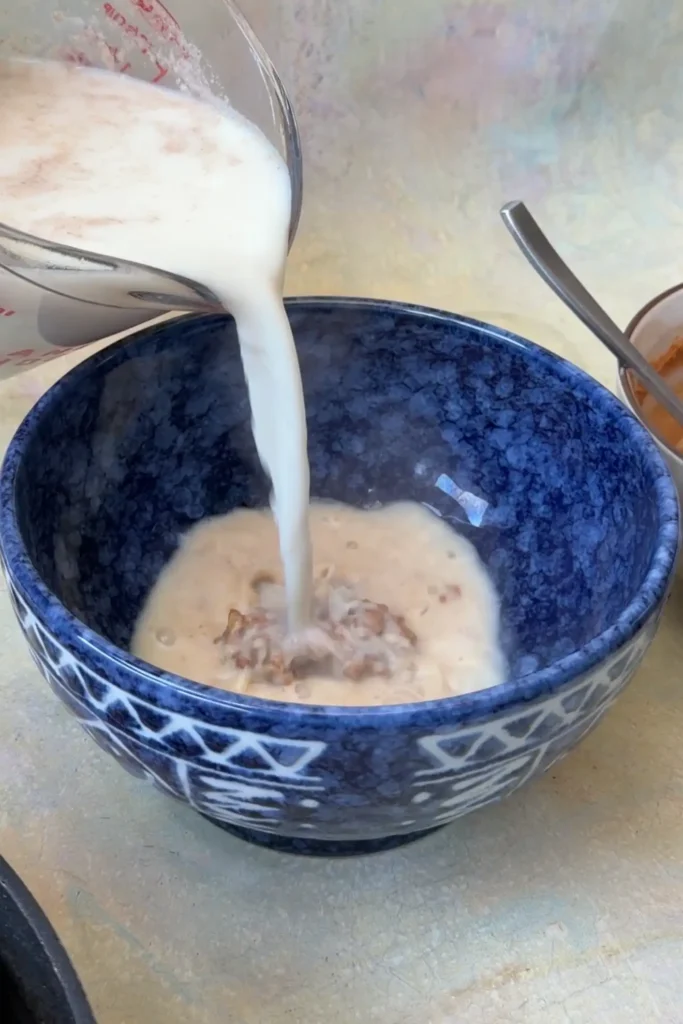 Hot sesame broth being poured into a serving bowl to make tantanmen ramen