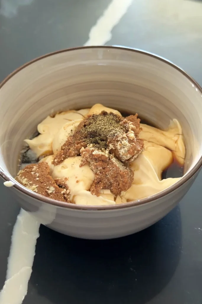 Mayonnaise, liver spread, liquid seasoning, lemon juice, and black pepper in a bowl for sisig sauce.