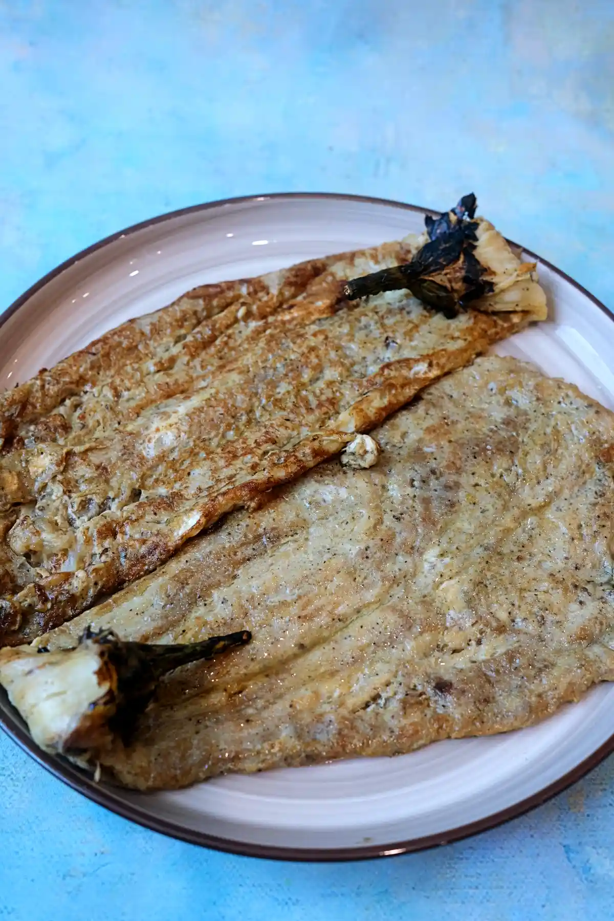 Two freshly cooked tortang talong omelets served on a plate.