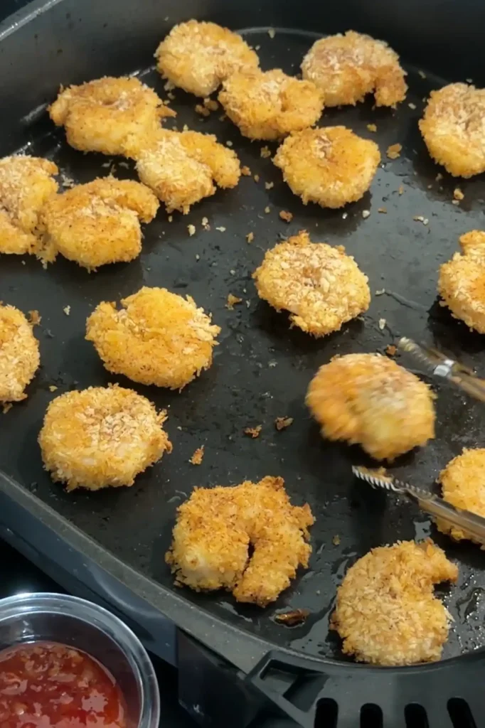 Air fryer popcorn shrimp flipped halfway through cooking for an even crispy golden coating