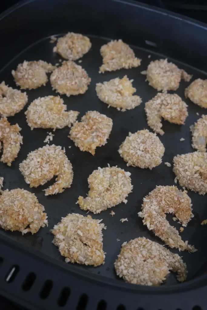 Panko breaded shrimp arranged in an air fryer basket before cooking