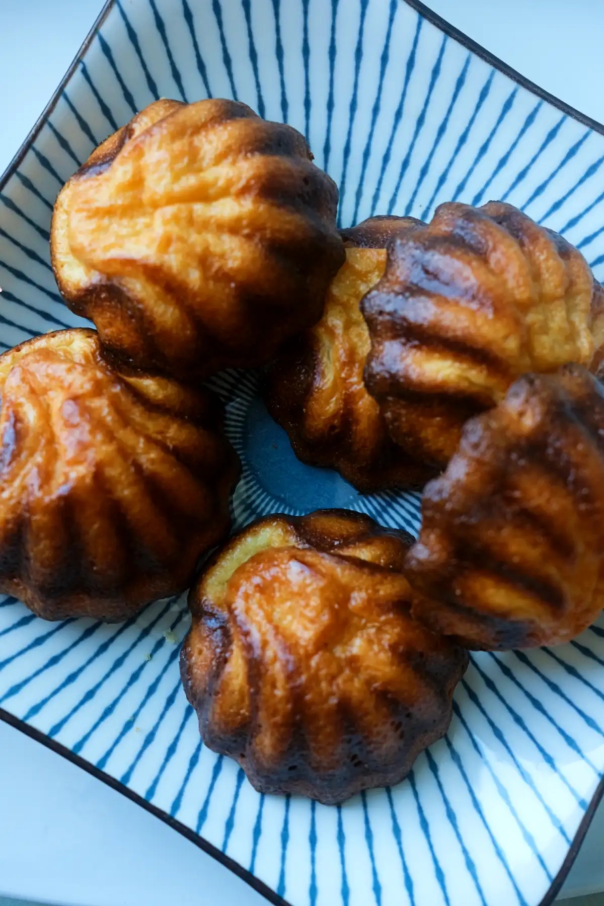 Close-up of butter tteok with crisp, caramelized edges on a striped plate.