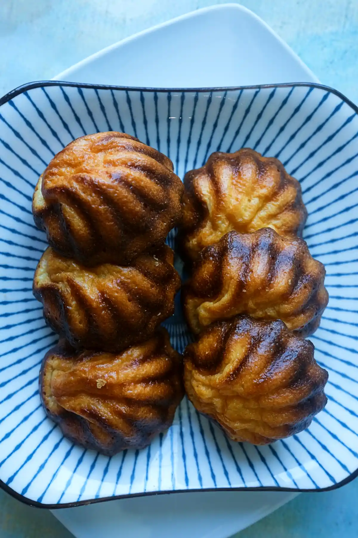 Butter tteok stacked on a striped plate with the front piece in sharp focus.