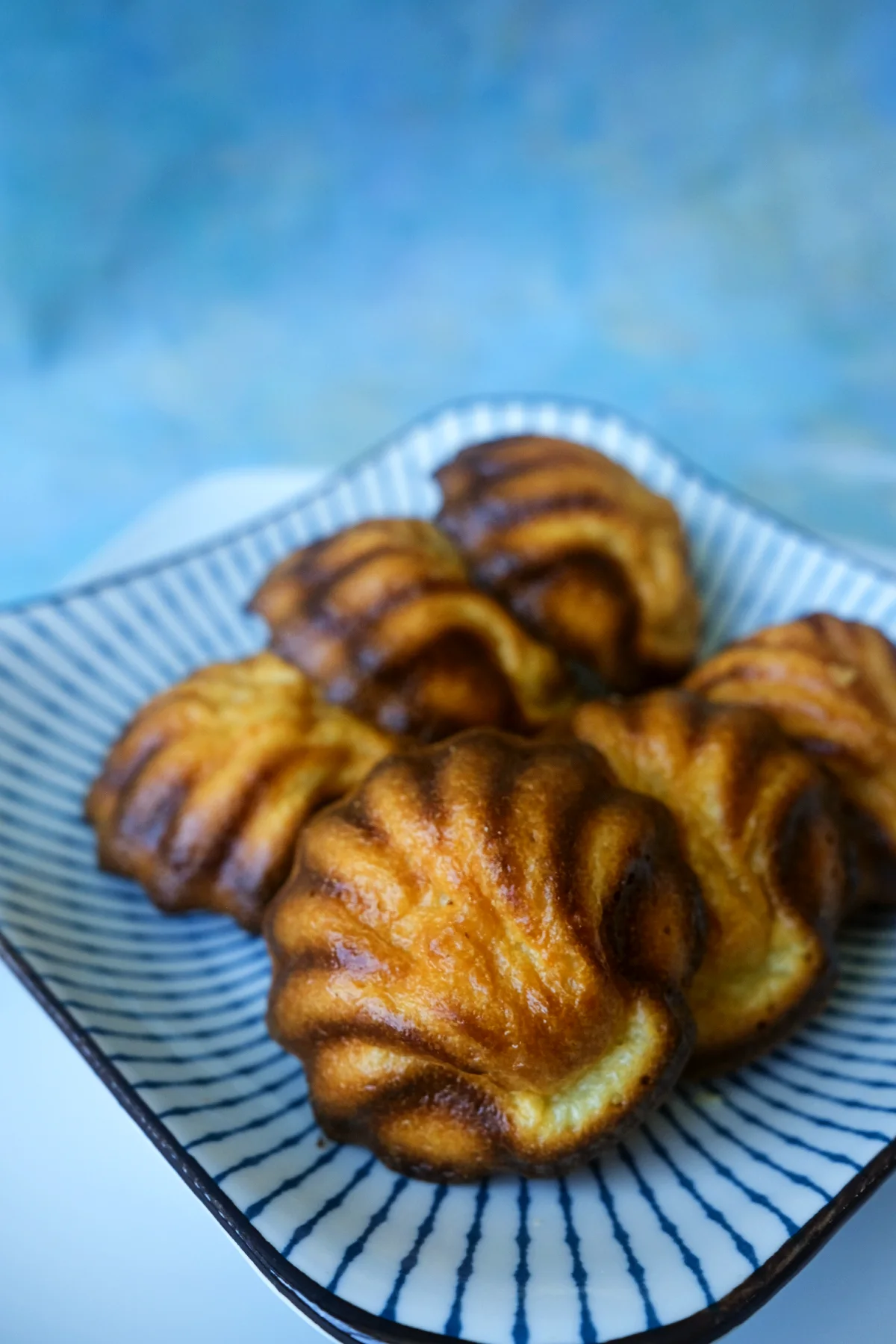 Six butter tteok arranged in two rows on a blue-and-white striped plate.