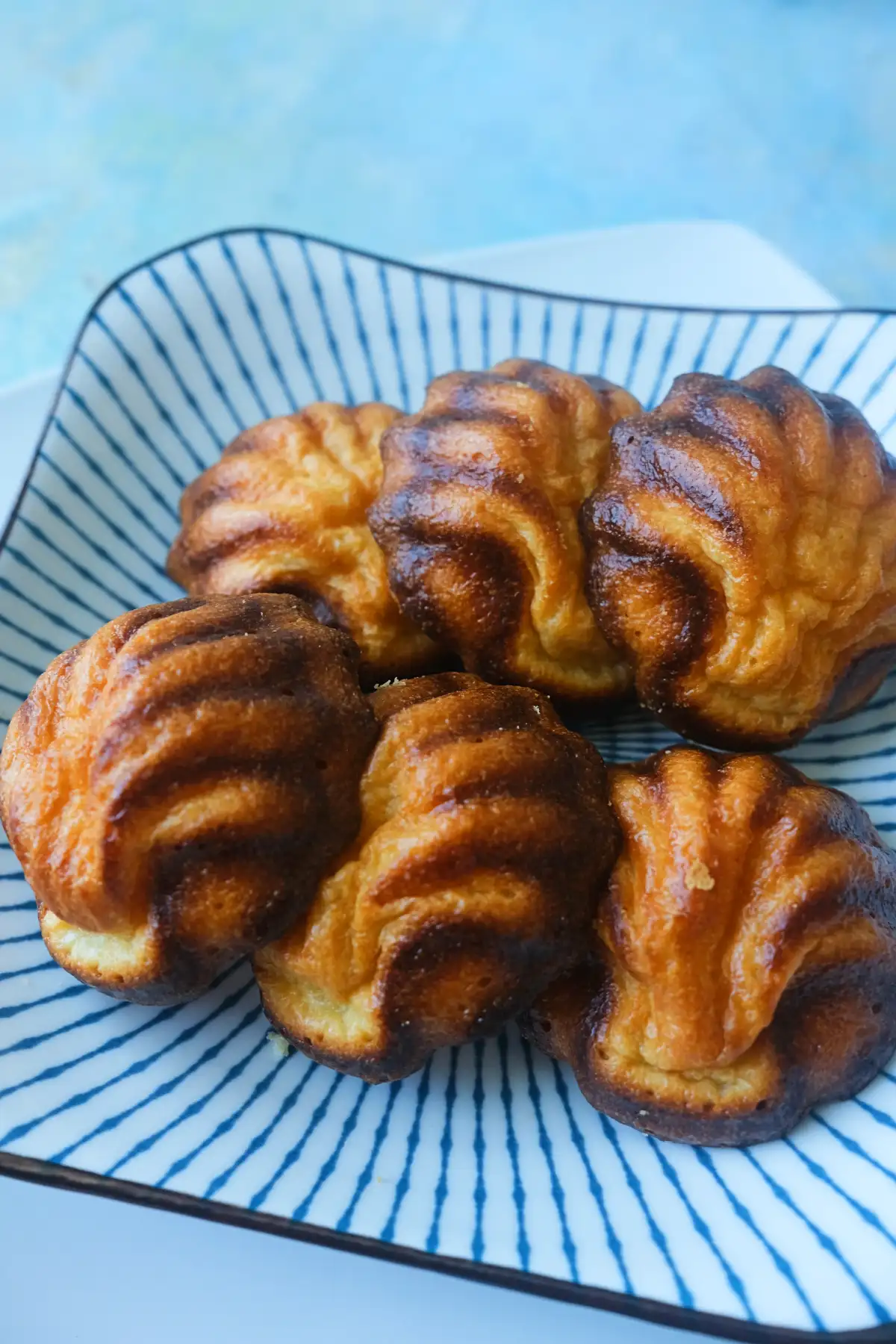Six butter tteok arranged in two rows on a blue-and-white striped plate.