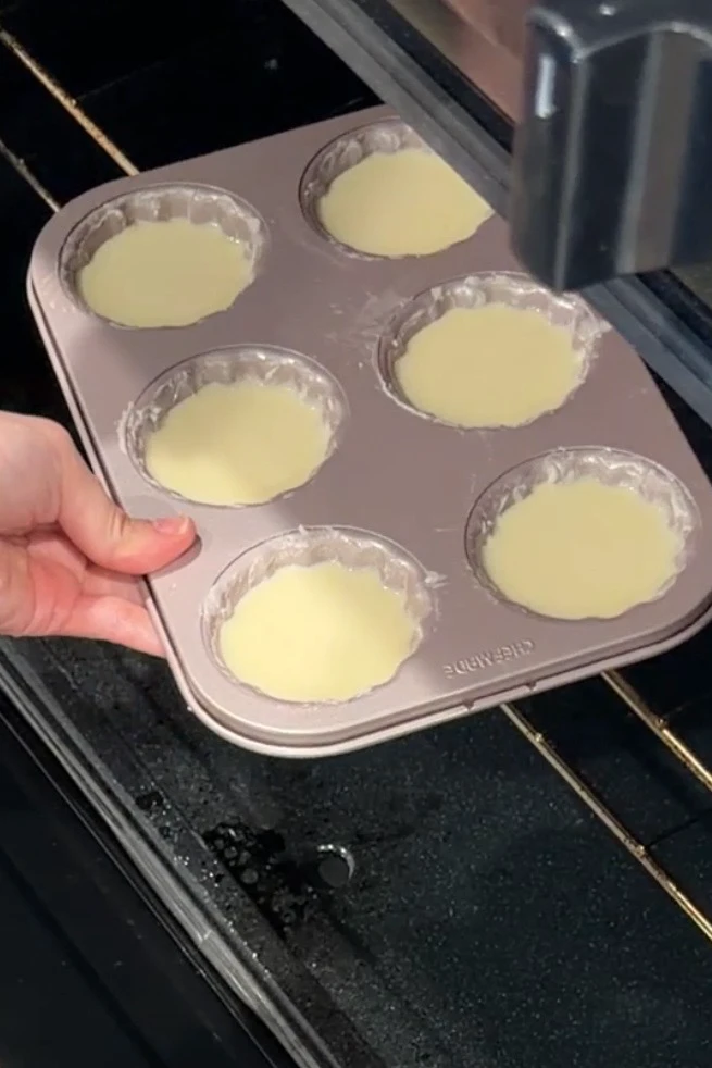 Filled madeleine pan being placed into the oven for baking.