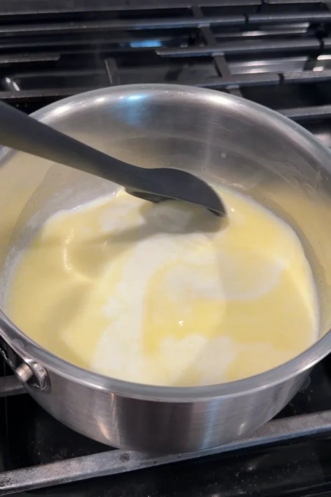 Butter melting into the warm milk in a saucepan.