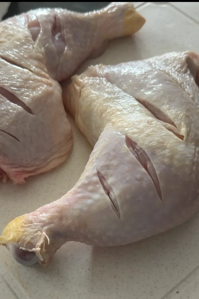 Chicken leg quarters scored to help the Chicken Inasal marinade absorb