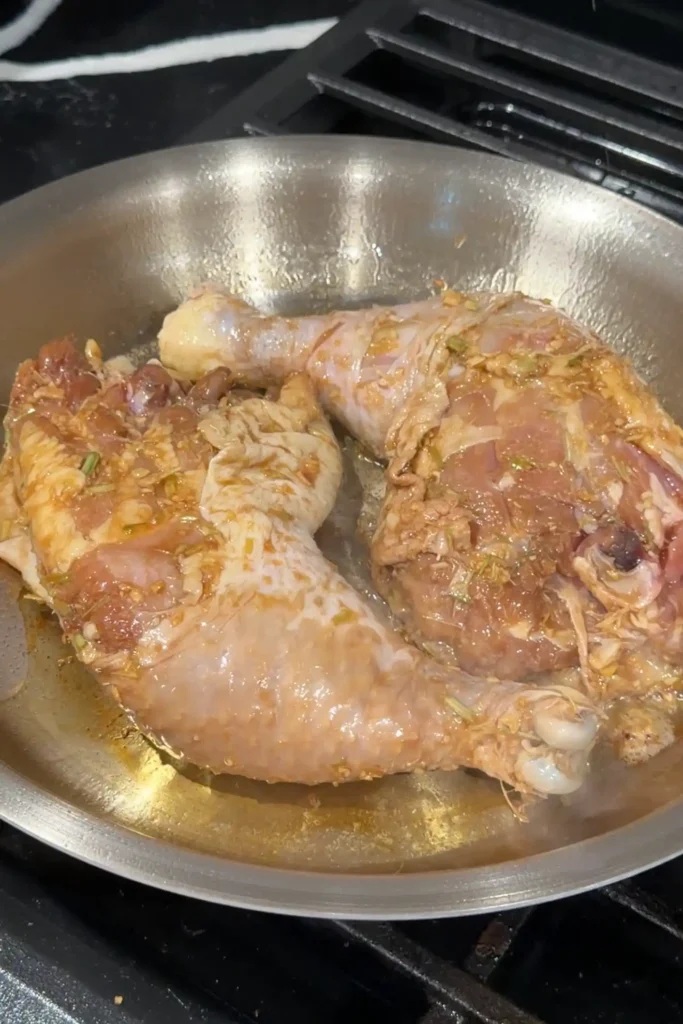 Searing Chicken Inasal in a skillet until the skin is golden brown