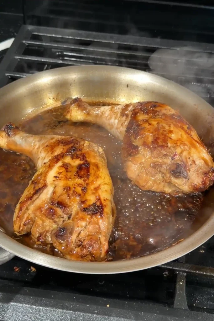 Chicken Inasal simmering in the reserved marinade until tender