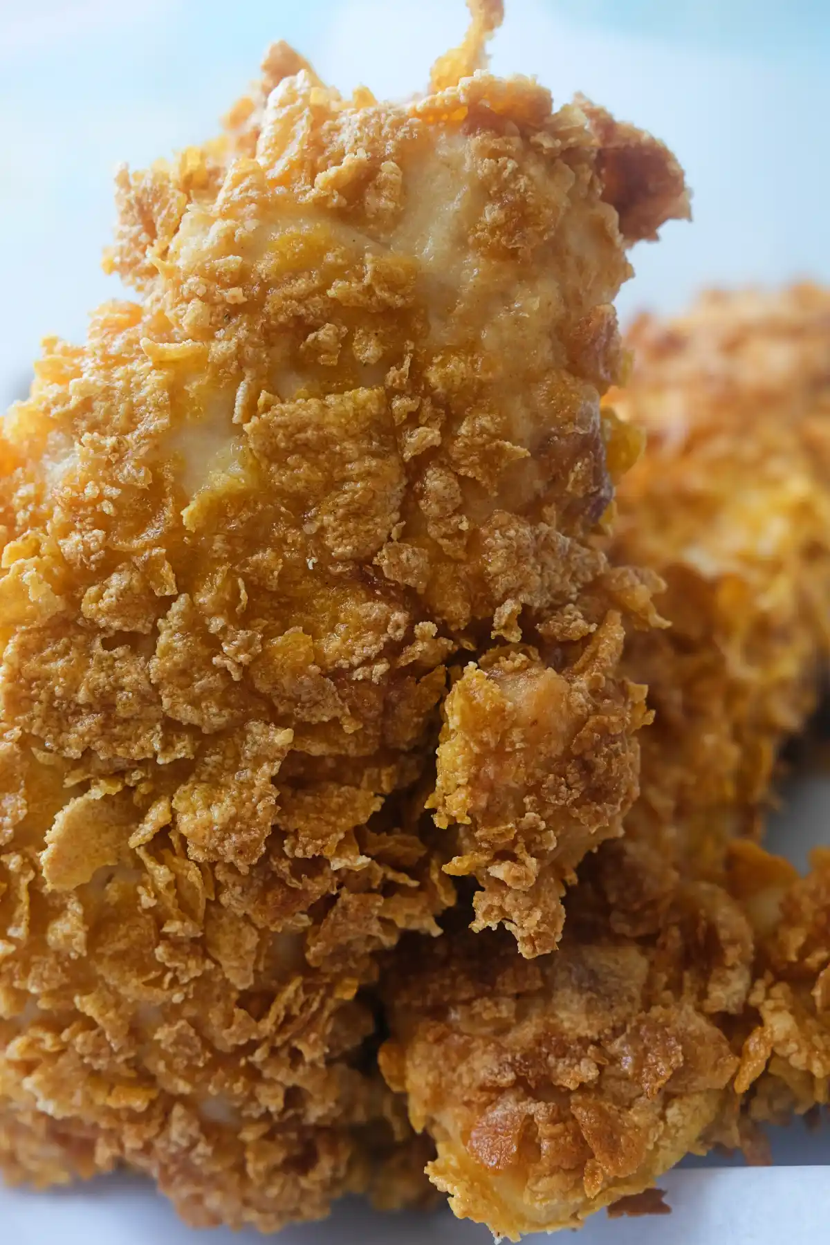 Close-up of crispy cornflake chicken tenders stacked to show the crunchy coating and juicy chicken inside.