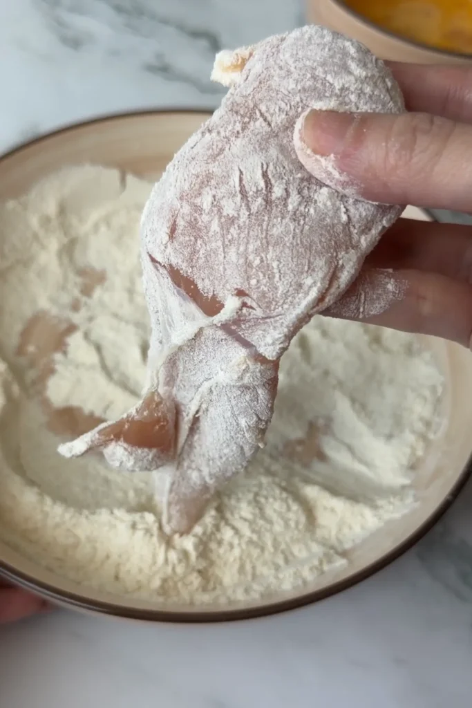 Chicken tender coated in flour before dipping into the egg.