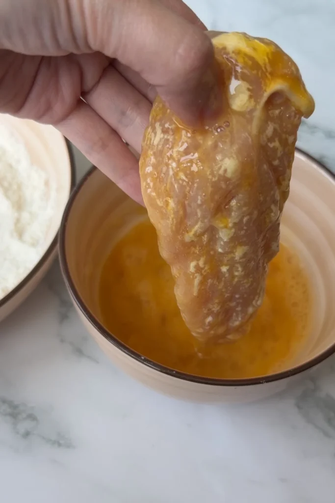Floured chicken tender dipped into beaten eggs before coating with cornflakes.
