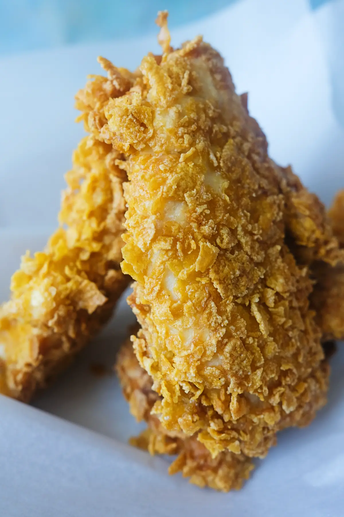 Close-up of cornflake chicken tenders with a crispy golden coating and juicy chicken center.