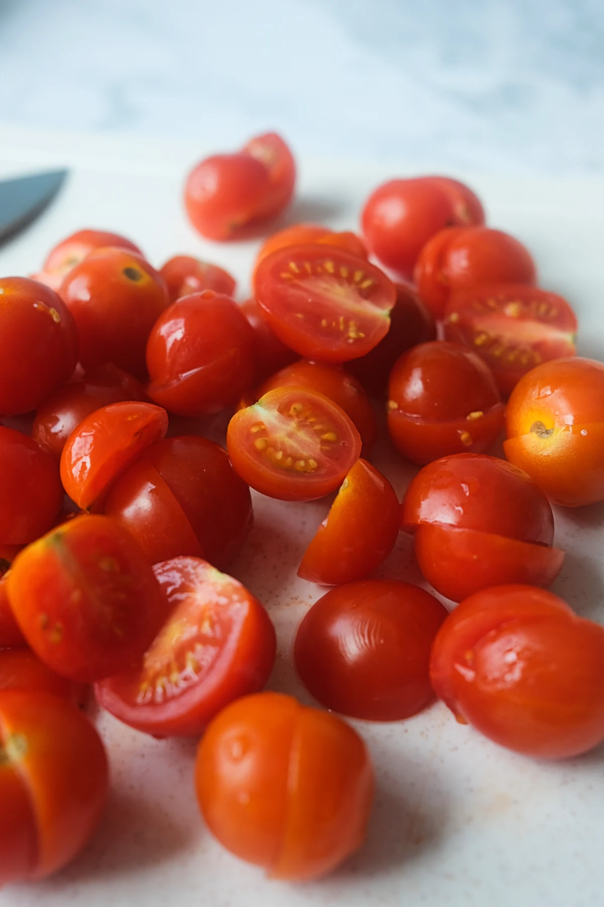 Fresh cherry tomatoes, halved and whole, spread across a cutting board.
