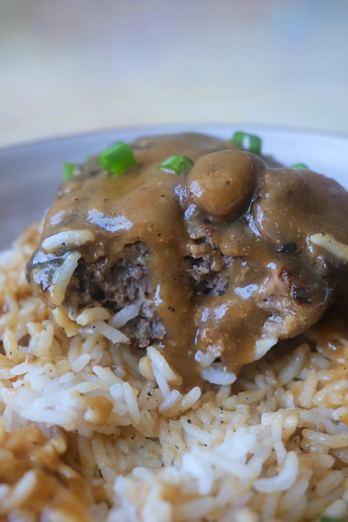 Close-up of a hamburger steak patty showing the juicy beef center with mushroom gravy.