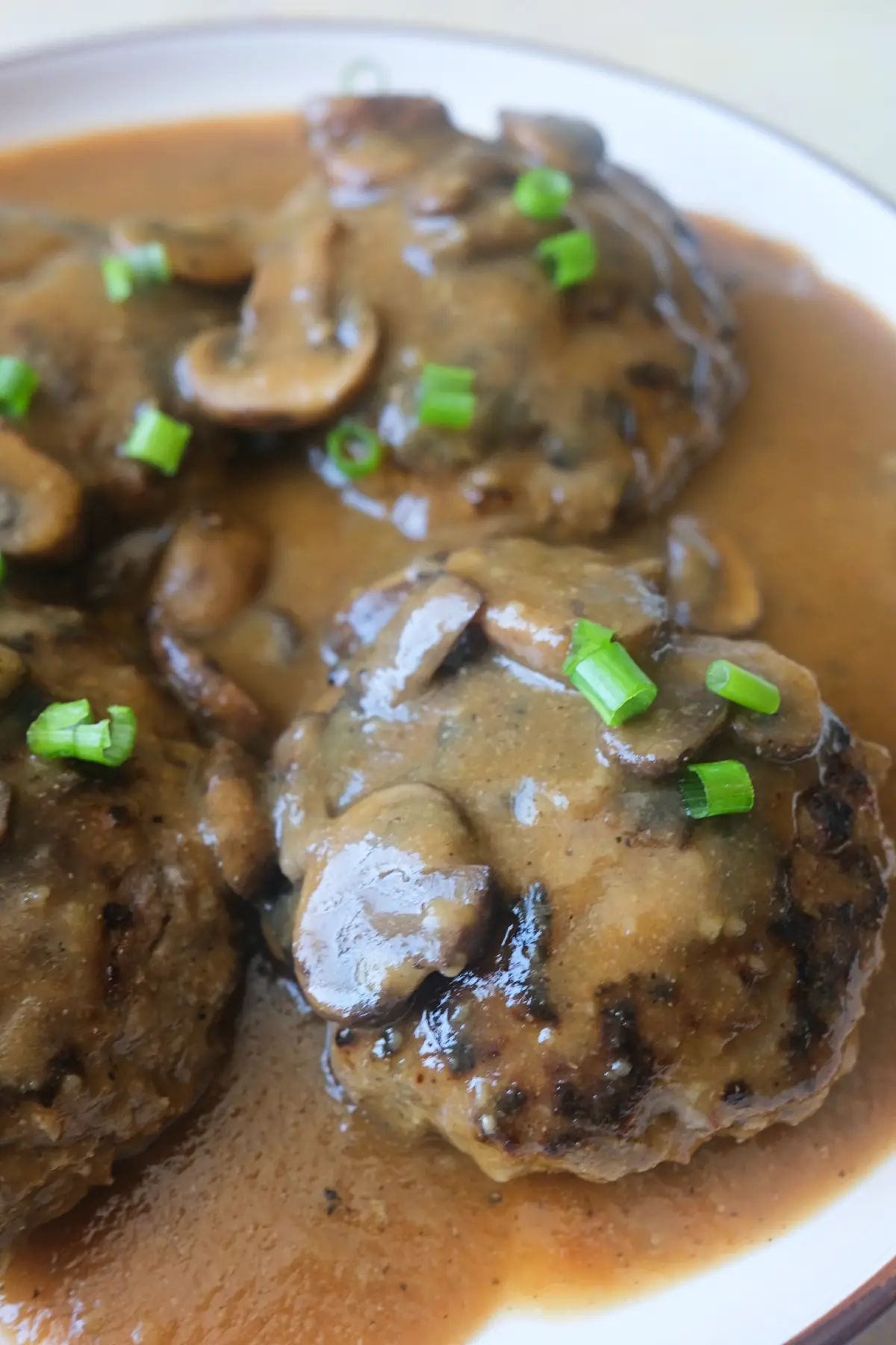 Hamburger steak with mushroom gravy showing tender beef patties, mushrooms, and glossy brown sauce.