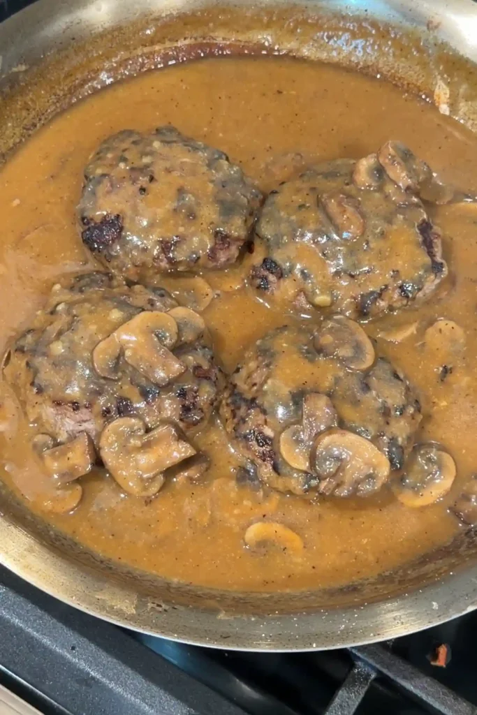 Juicy hamburger steaks covered in thick mushroom gravy, ready to serve with rice.