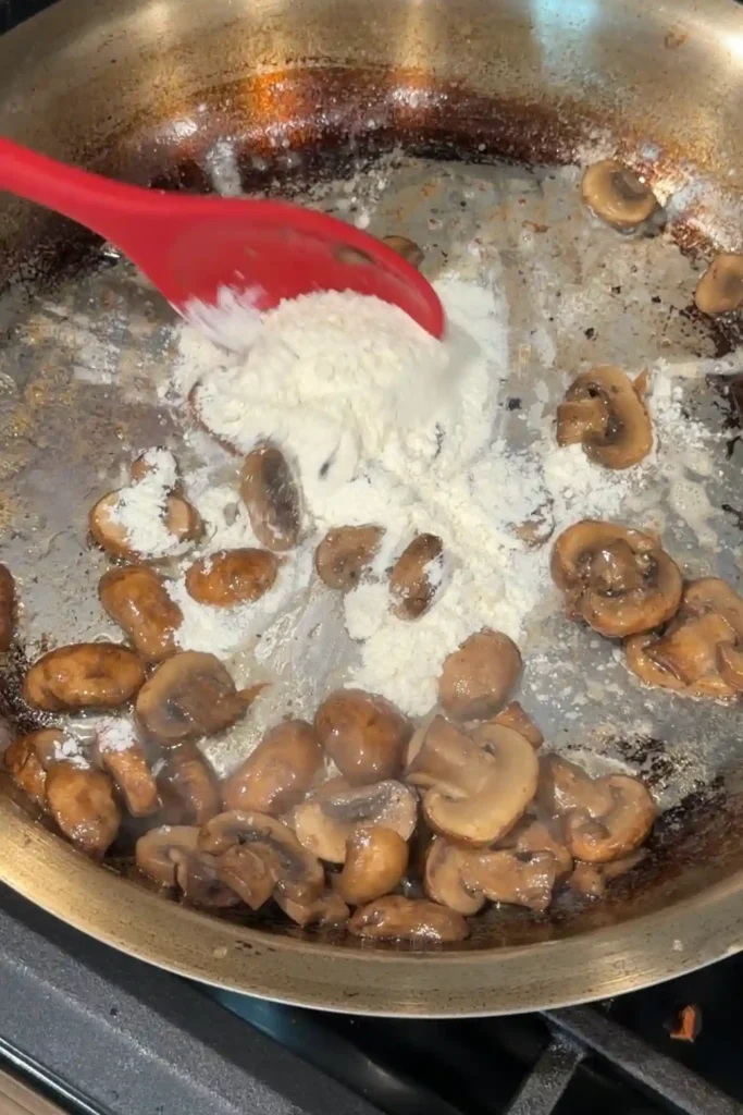 Flour added to sautéed mushrooms to create a roux for homemade mushroom gravy.
