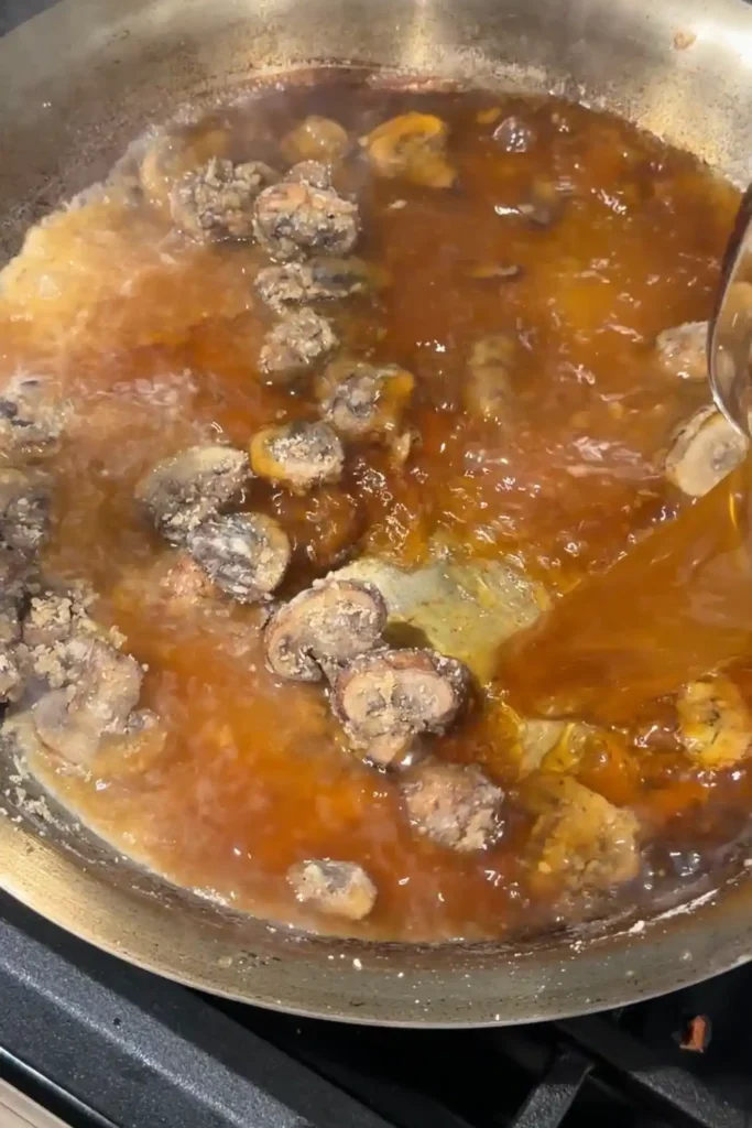 Beef broth added to mushroom roux while making a rich brown mushroom gravy.