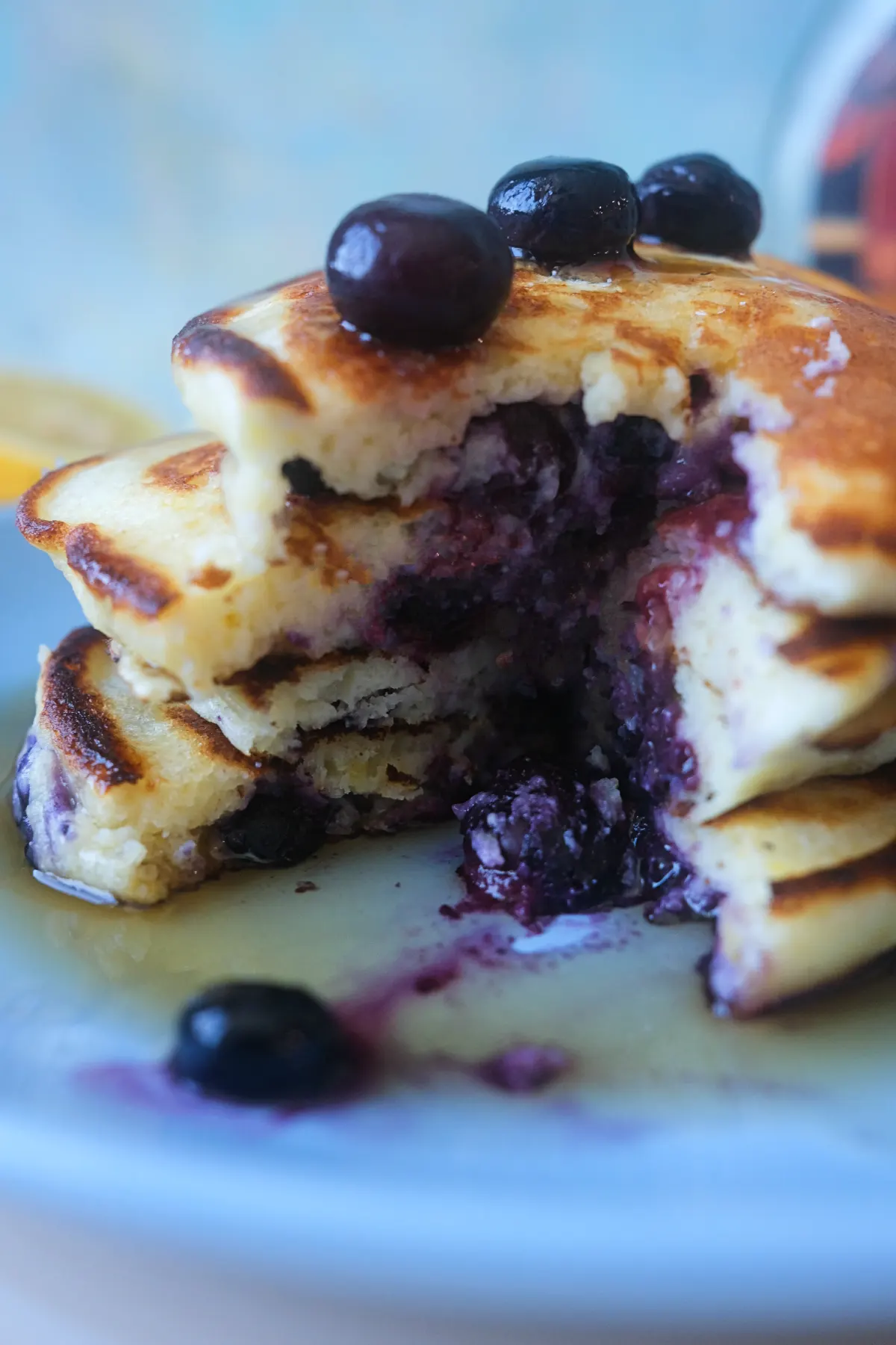 Cut-open lemon blueberry ricotta pancakes showing a soft, fluffy center filled with juicy blueberries and maple syrup.