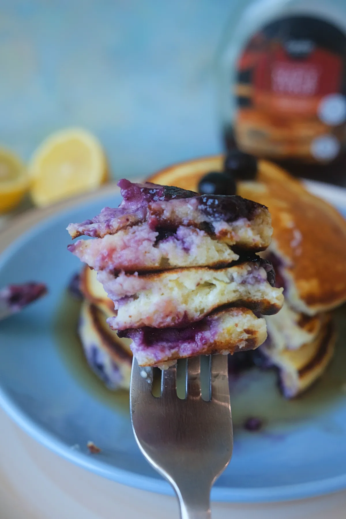 Bite-sized piece of lemon blueberry ricotta pancakes on a fork showing the fluffy interior and juicy blueberries.
