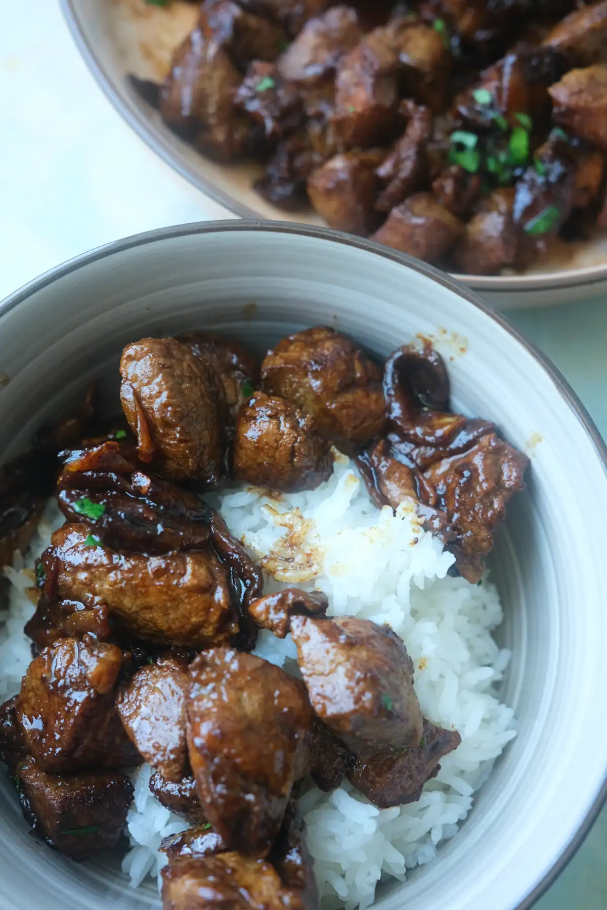 Pork salpicao served over steamed white rice with an extra platter of pork salpicao in the background.