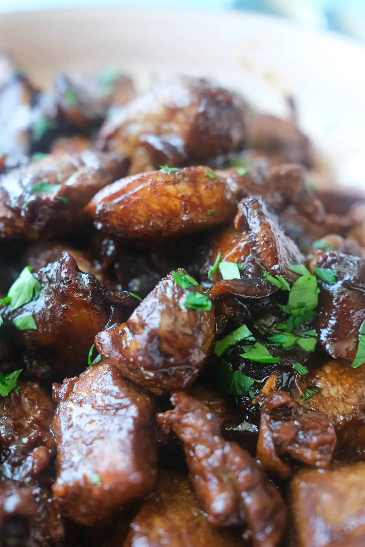 Close-up of pork salpicao with browned garlic cloves and chopped parsley in a shallow serving dish.