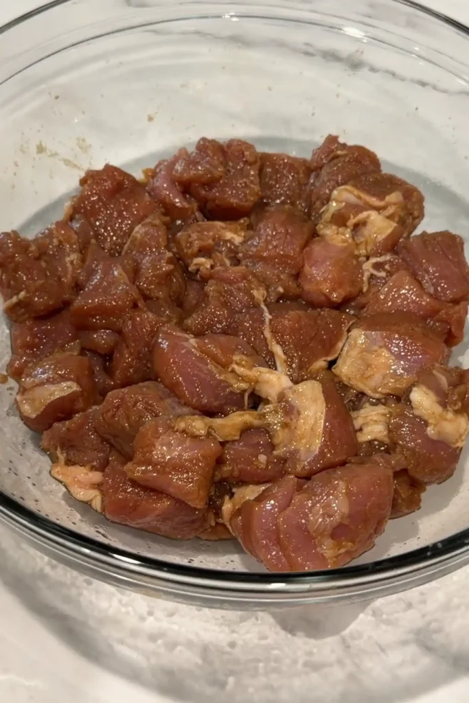 Marinated pork loin in a glass bowl after the seasonings have been absorbed into the meat.