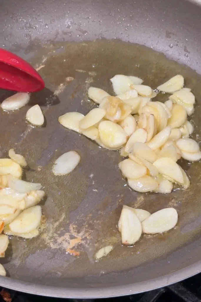 Thinly sliced garlic cooking in butter and oil in a skillet until lightly golden.
