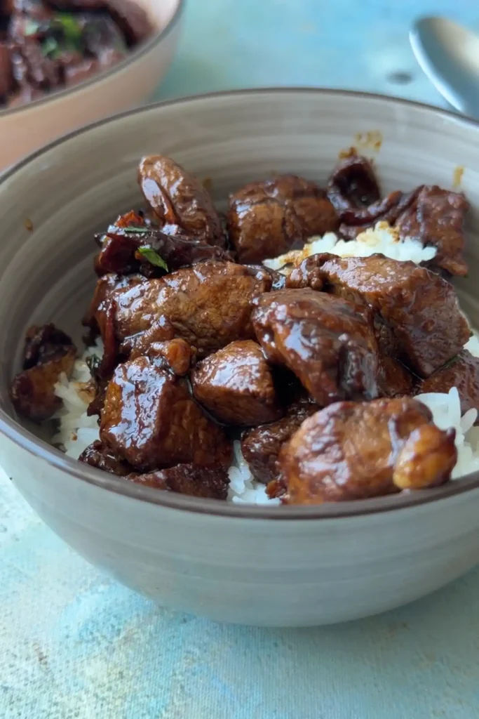 Bowl of steamed white rice topped with pork salpicao, crispy garlic, and garlic butter sauce.