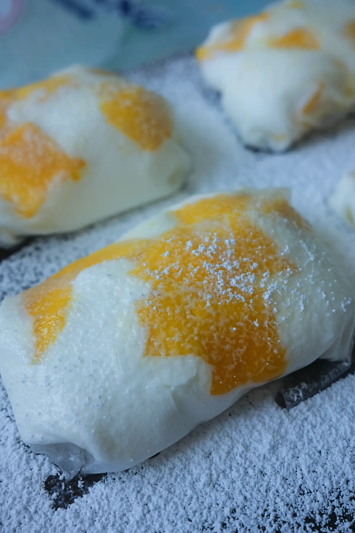 Several pieces of rice paper mango mochi on a serving board, showcasing the soft wrapper and bright mango pieces inside.