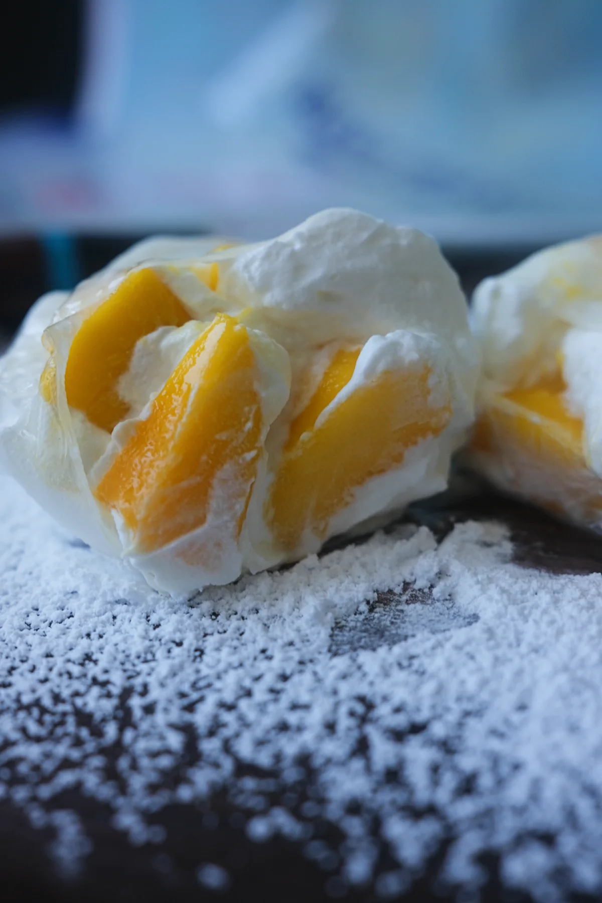 Close-up of the creamy whipped mango filling and fresh mango chunks inside a sliced rice paper mango mochi.