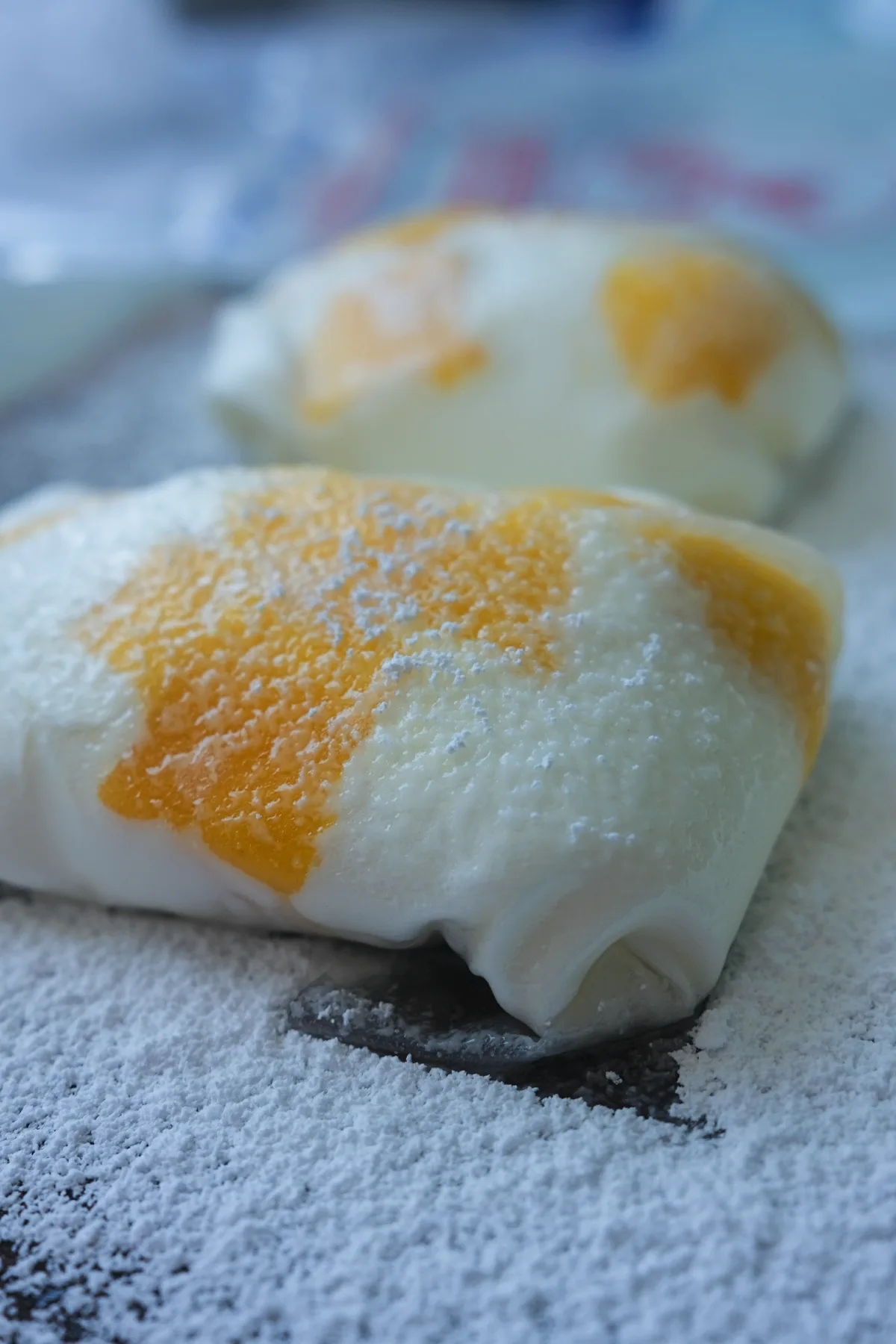 Two pieces of rice paper mango mochi with fresh mango pieces showing through the chewy rice paper wrapper.