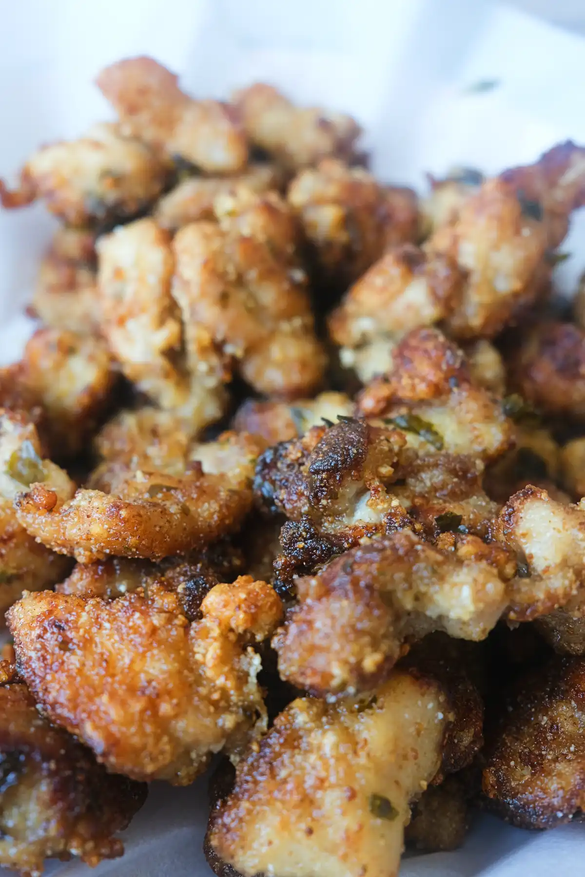 Close-up of Taiwanese popcorn chicken with a crunchy golden coating and scattered fried basil.