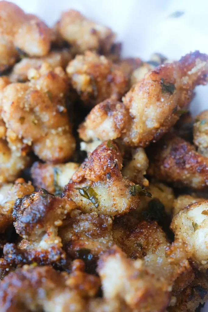 Close-up of Taiwanese popcorn chicken with a crispy golden coating and pieces of fried basil throughout.