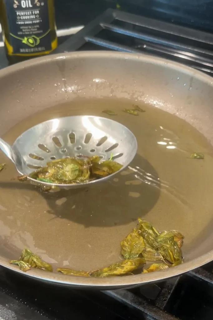 Crispy fried basil leaves lifted from the hot oil with a slotted spoon.