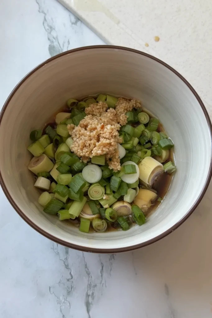 Bowl of Vietnamese lemongrass chicken marinade made with chopped lemongrass, scallions, garlic, fish sauce, soy sauce, brown sugar, lime juice, and seasonings before adding the chicken.