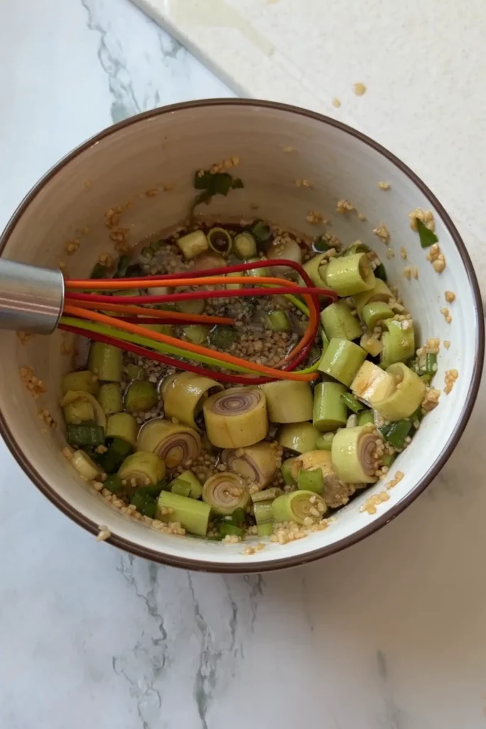 Vietnamese lemongrass chicken marinade being mixed together with fresh lemongrass, garlic, green onions, fish sauce, and other ingredients to create a flavorful chicken marinade.