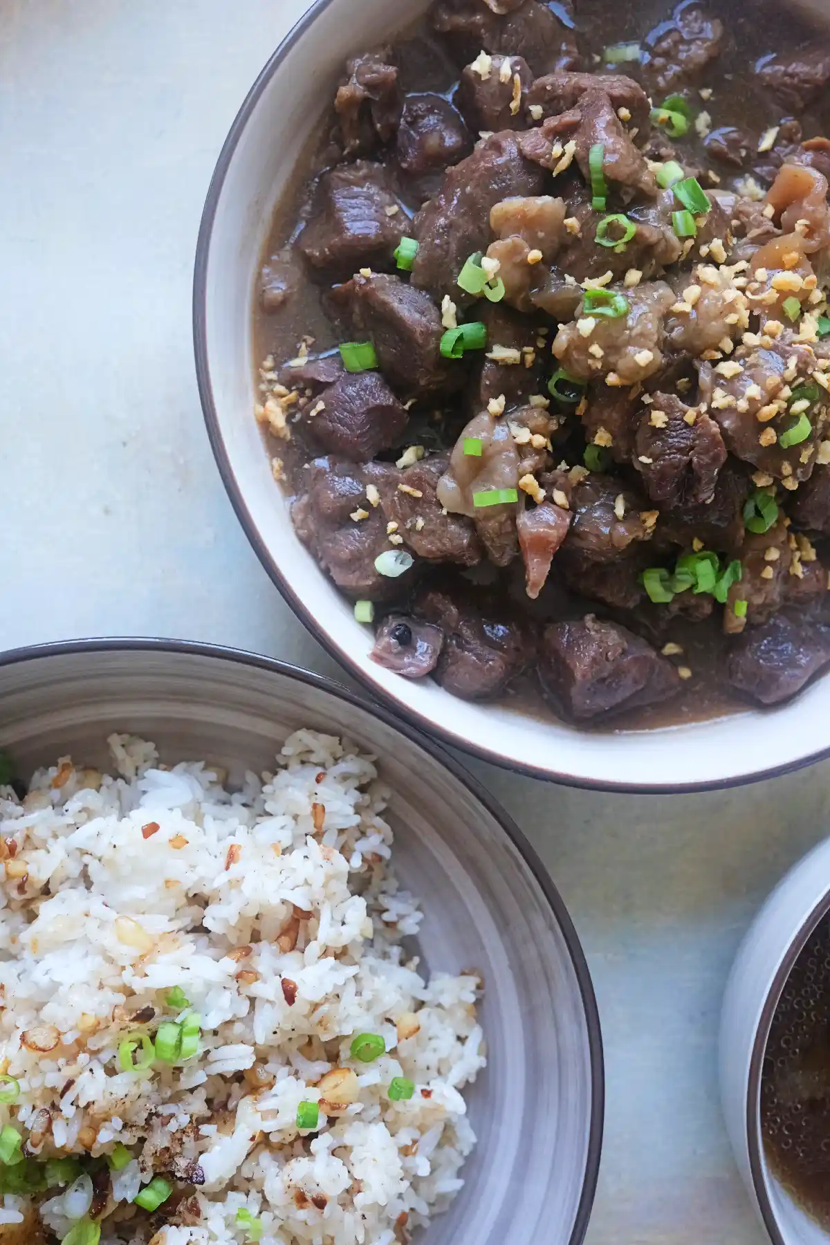 Filipino beef pares topped with fried garlic and green onions, served with garlic fried rice and beef broth.