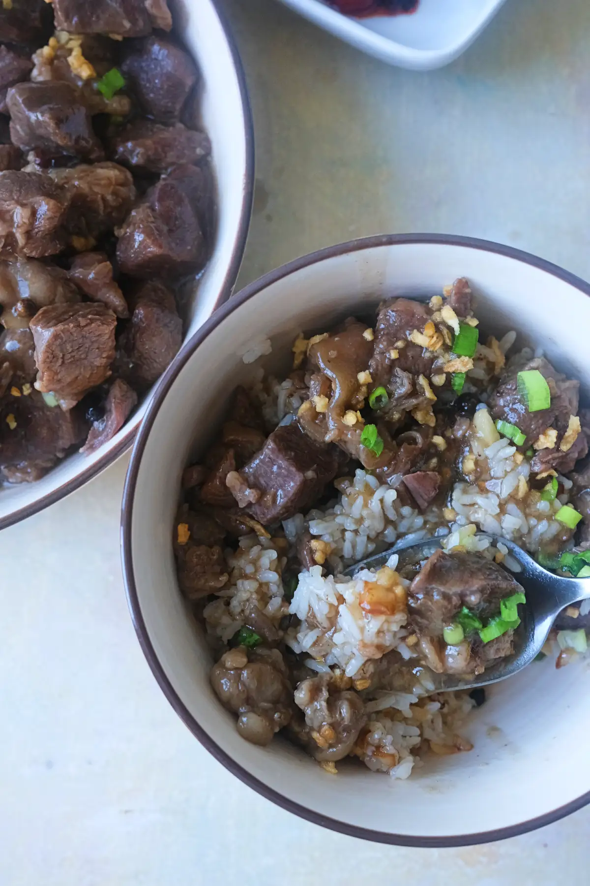 Spoonful of beef pares with tender beef, garlic fried rice, and sweet and savory sauce.