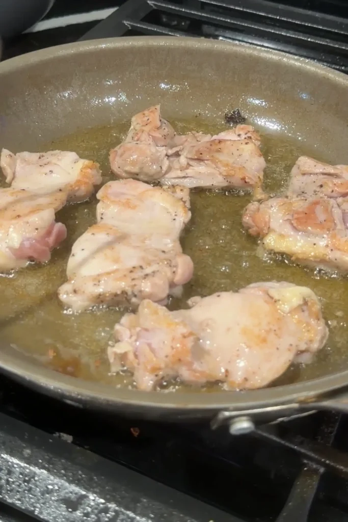 Chicken pieces browning in oil for chicken pochero