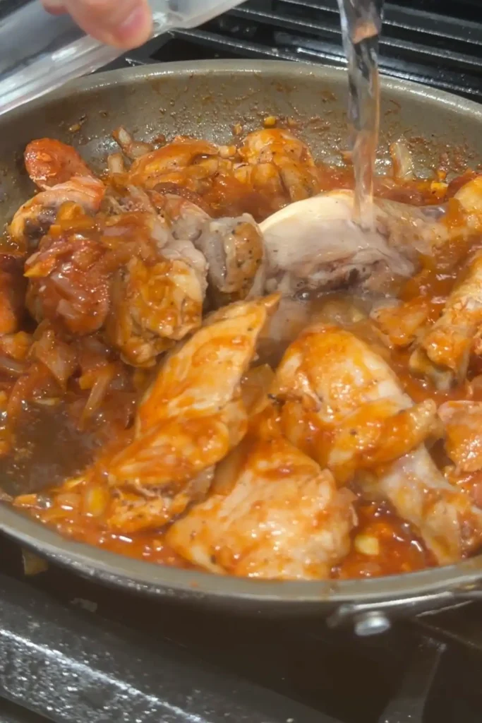 Water being added to chicken and chorizo for chicken pochero